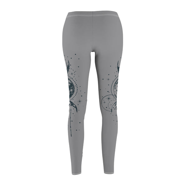 Rear view of gray leggings featuring a vertical hand-drawn illustration of moon phases and geometric arrows on the left leg. The fabric has a soft, brushed suede texture with visible white stitching at the waist and hem.