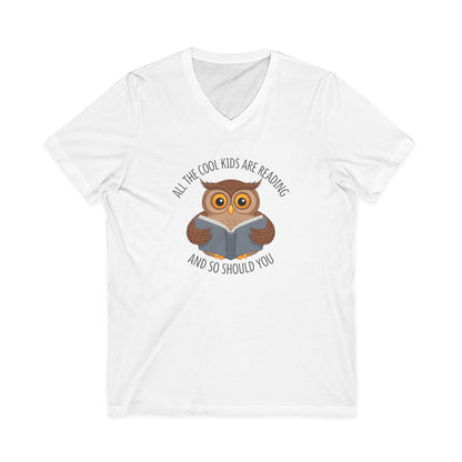 White v-neck t-shirt featuring a cartoon owl reading a book with the text All The Cool Kids Are Reading And So Should You.